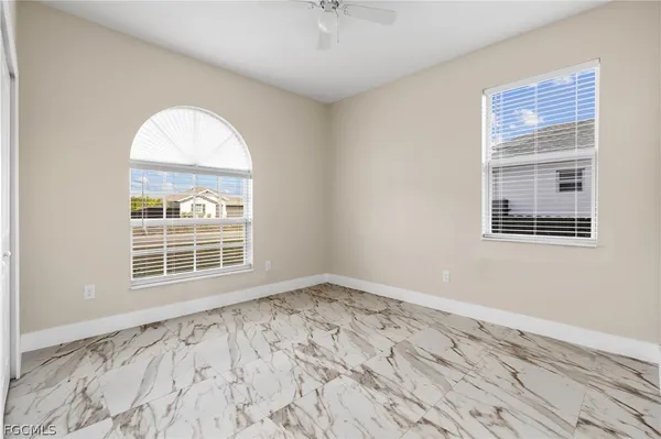 an empty room with wooden floor cabinet and windows