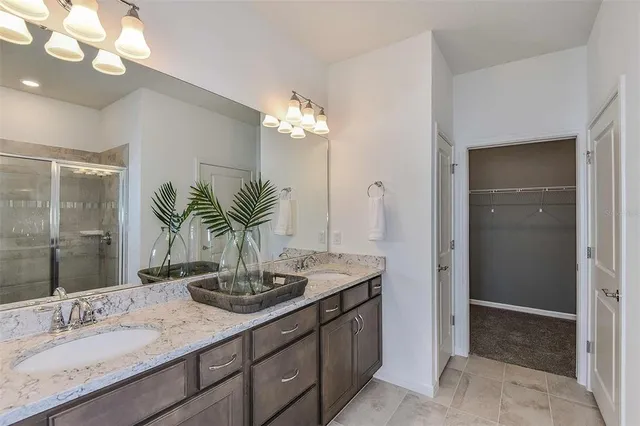 a bathroom with a granite countertop sink a large mirror and a shower