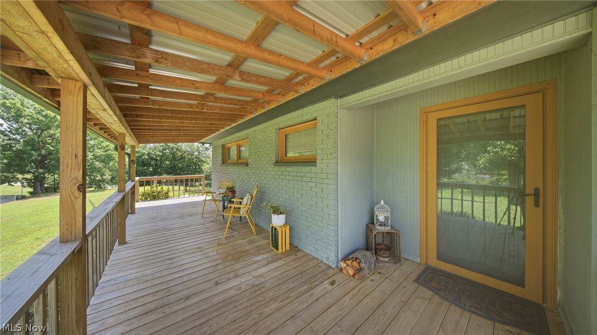 89 Dagg Road Parkersburg, WV 26101 - Photo 11 of 45 Expansive covered porch featuring wood decking, a wooden railing, and an exposed beam ceiling with a metal roof