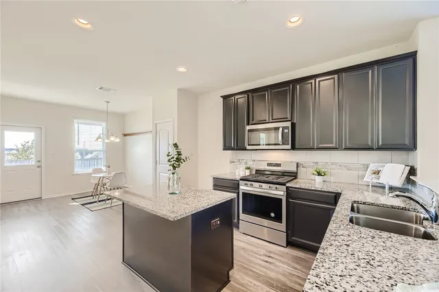 a kitchen with stainless steel appliances granite countertop a sink stove and refrigerator