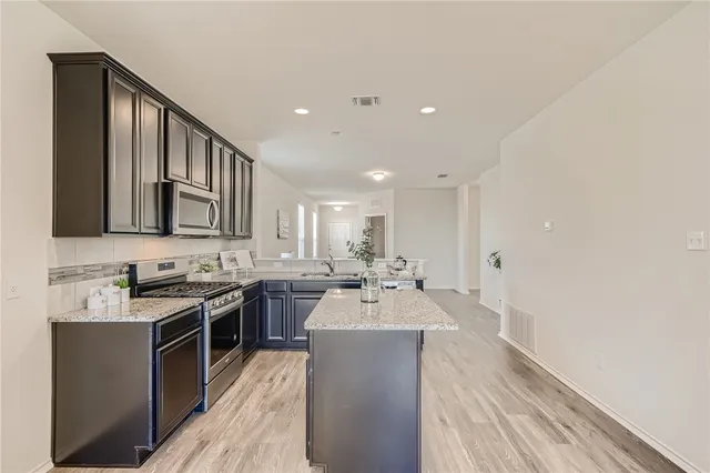 a large kitchen with a sink and a stove top oven with wooden floor