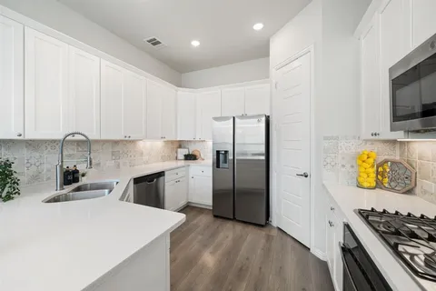 a kitchen with stainless steel appliances granite countertop a refrigerator a stove and a sink with wooden floor