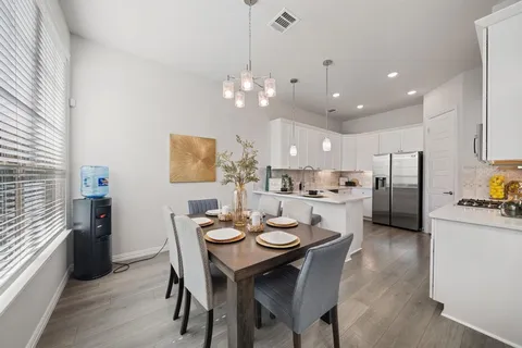 a view of a dining room and livingroom with furniture a chandelier and kitchen view