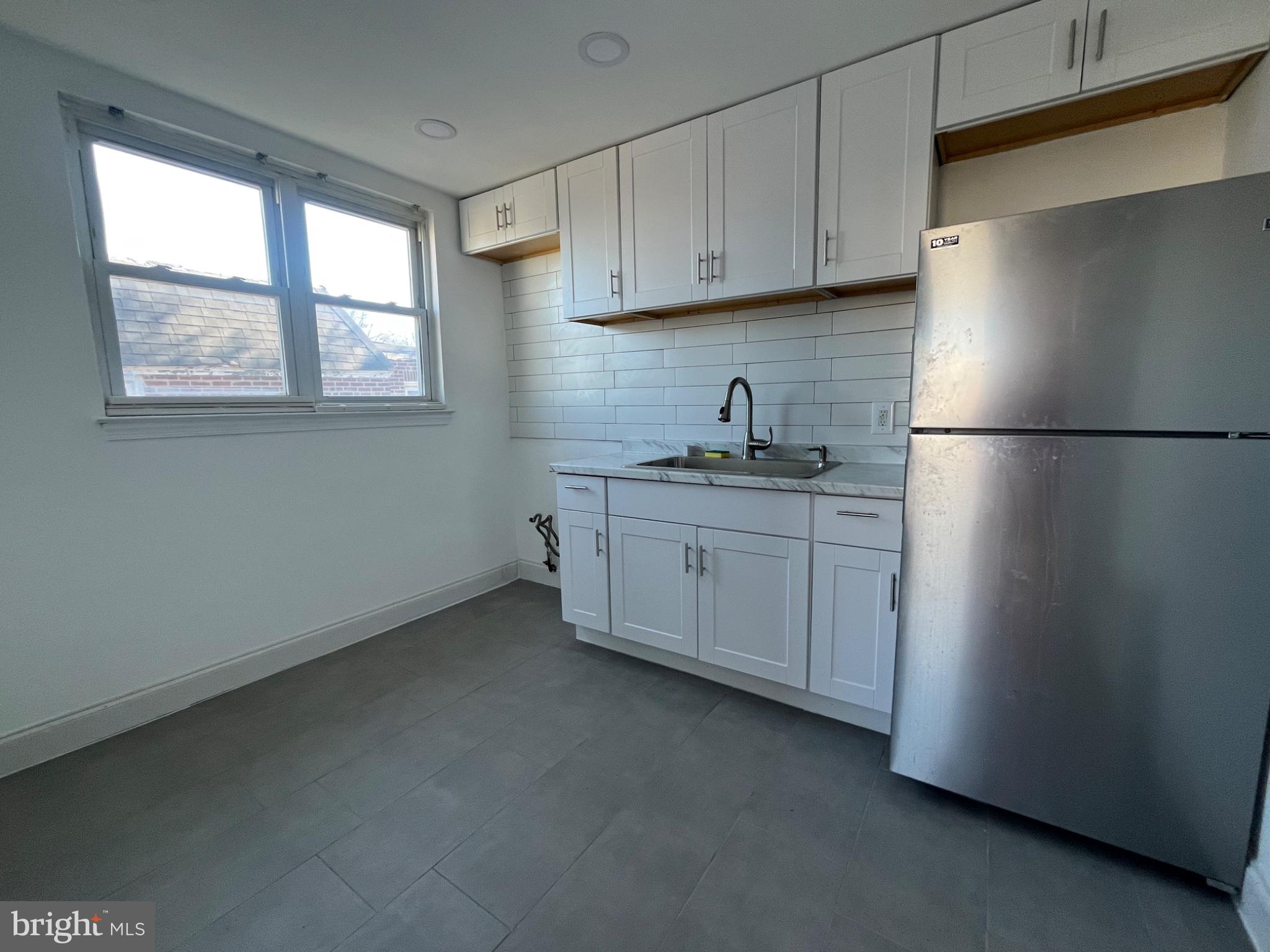 914 East Sharpnack Street Philadelphia, PA 19150 - Photo 3 of 5 a kitchen with a refrigerator sink and cabinets