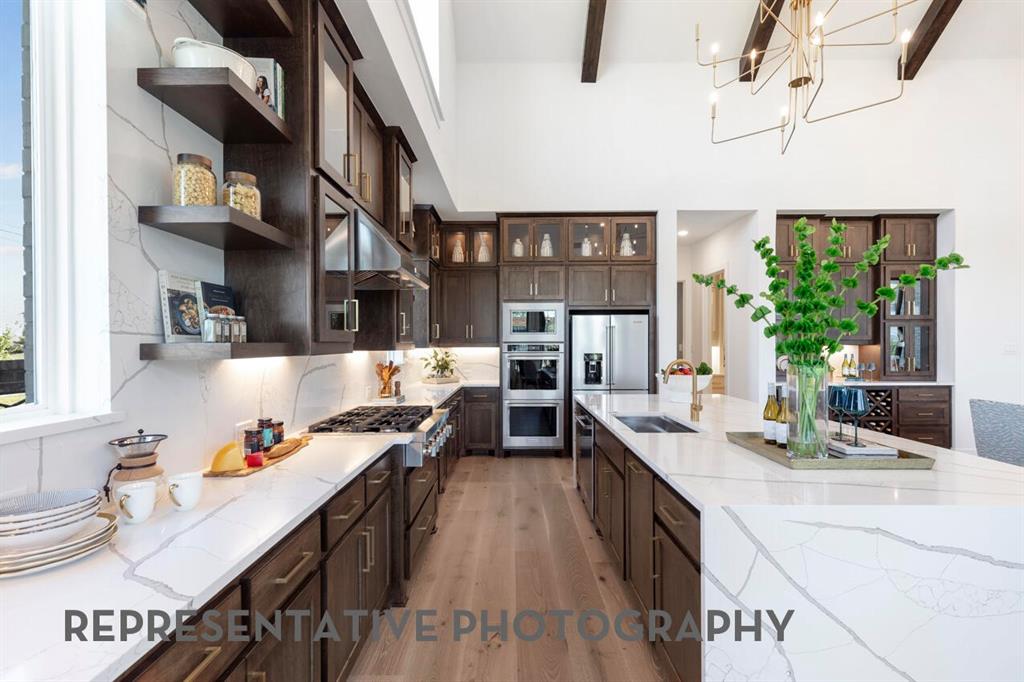 3908 Meander Way Prosper, TX 75078 - Photo 5 of 37 a large kitchen with stainless steel appliances granite countertop a lot of counter space and a sink