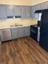 a kitchen with granite countertop a refrigerator and a stove top oven