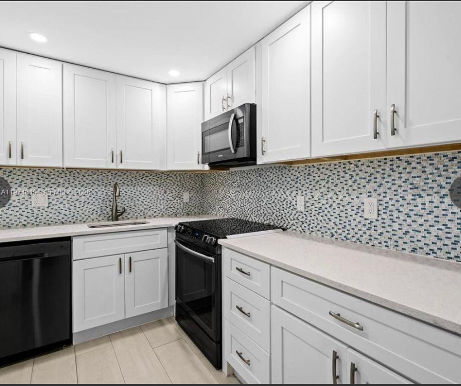1505 North Riverside Drive, Unit 505 Pompano Beach, FL 33062 - Photo 4 of 9 a kitchen with granite countertop white cabinets and stainless steel appliances