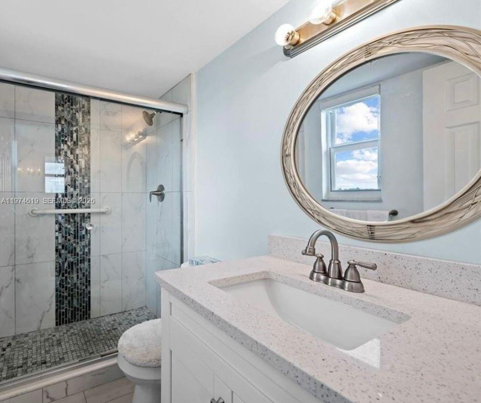 1505 North Riverside Drive, Unit 505 Pompano Beach, FL 33062 - Photo 5 of 9 a bathroom with a sink a toilet and a mirror