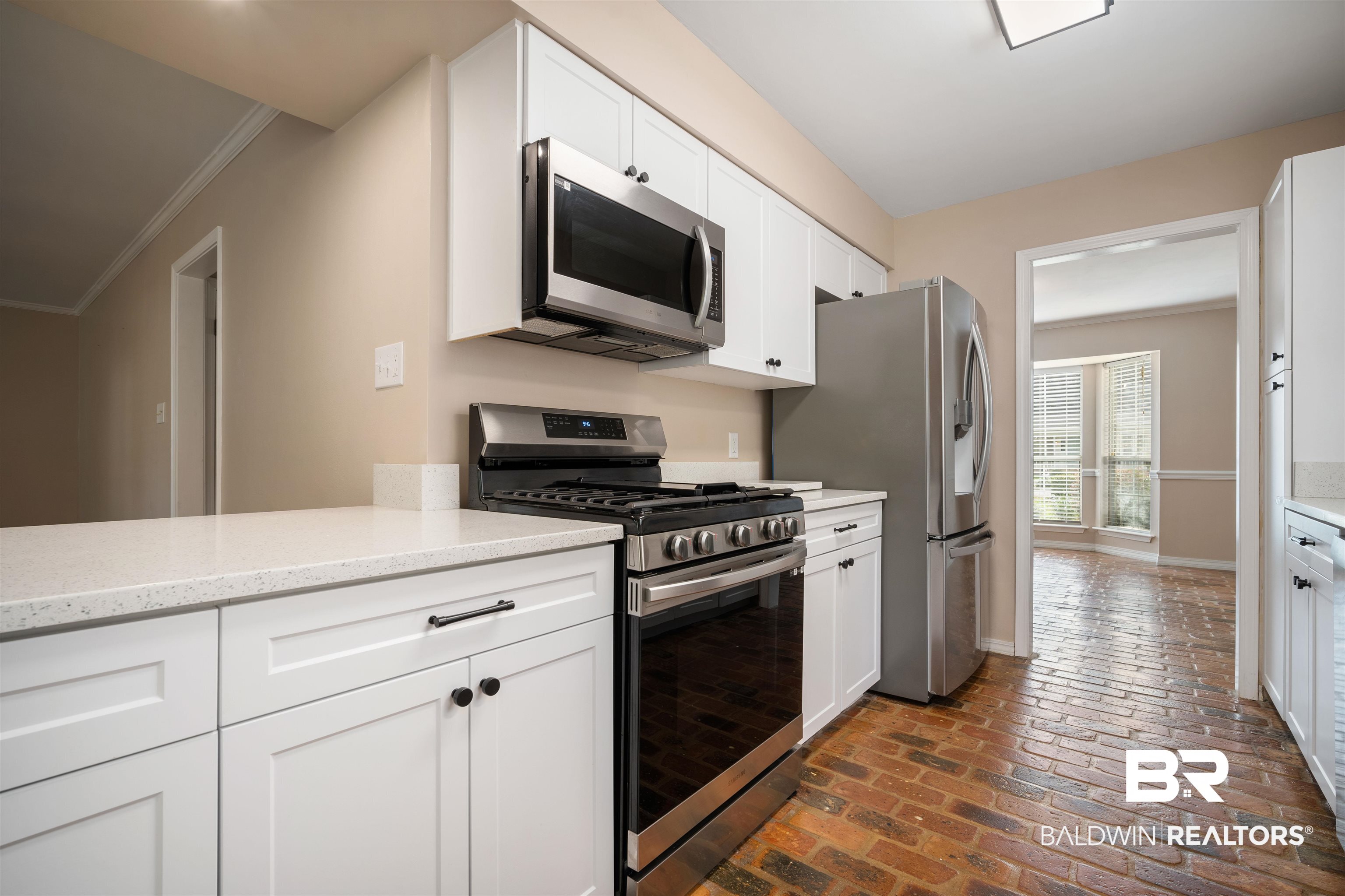 804 Wildwood Avenue Mobile, AL 36609 - Photo 10 of 30 Kitchen featuring crown molding, light stone counters, appliances with stainless steel finishes, and white cabinets