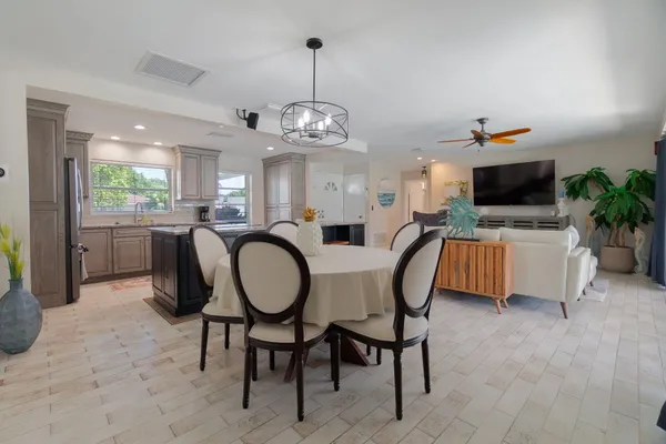 a dining room with wooden floor a chandelier a wooden table and chairs