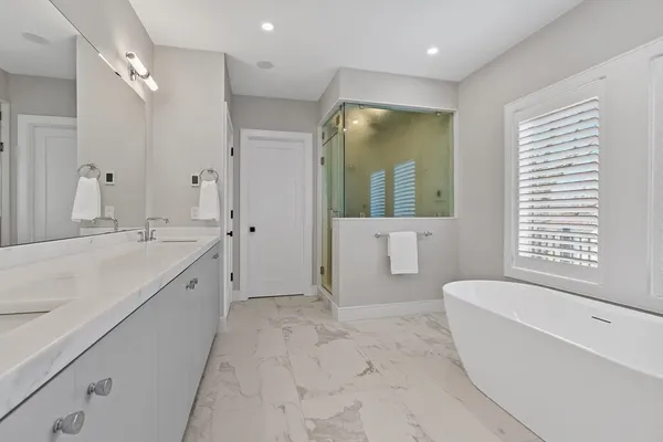 a spacious bathroom with a tub sink shower and mirror