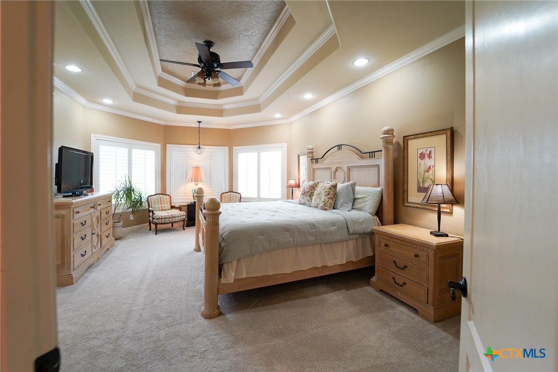 501 Barbara Street Ganado, TX 77962 - Photo 13 of 43 Here, the primary bedroom with architecturally pleasing ceiling detail and crown moldings is a spacious respite that easily accommodates king size furnishings, with room to spare for a sitting area in front of the triple bay windows with custom wood shutters.