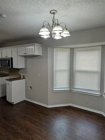 an empty room with wooden floor cabinet and a window