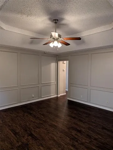 a view of an empty room with wooden floor and a ceiling fan