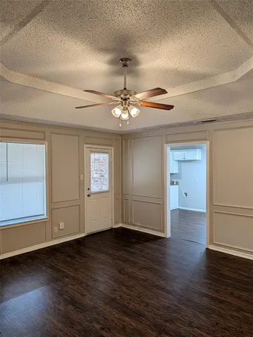 an empty room with wooden floor chandelier and windows