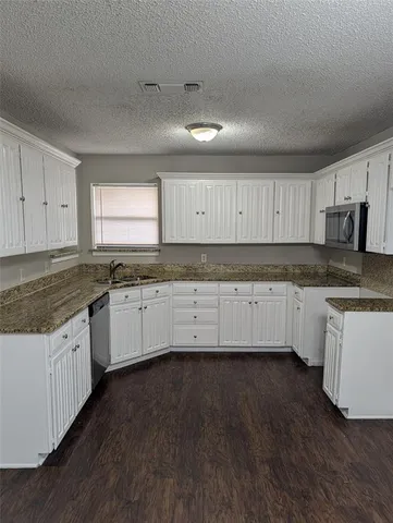 a kitchen with granite countertop a sink a stove a microwave and cabinets