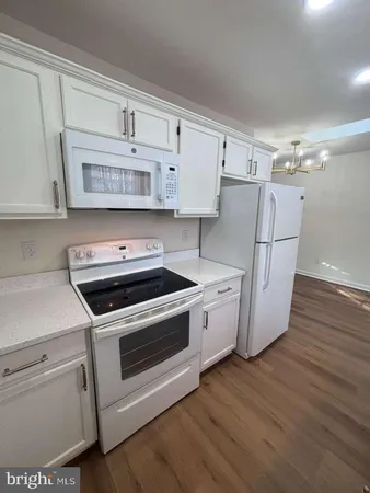 a kitchen with cabinets and wooden floor