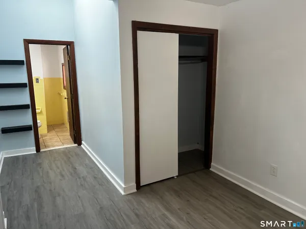 a view of an empty room with wooden floor and closet