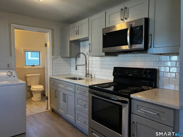 a kitchen with stainless steel appliances a stove a microwave a sink and cabinets