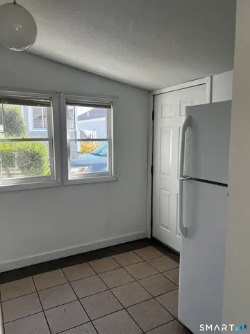 a view of an empty room with window and refrigerator
