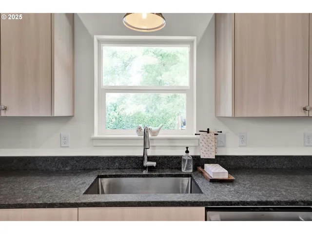 a kitchen with stainless steel appliances granite countertop a sink a counter space and a window
