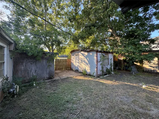 a view of a backyard with large trees and wooden fence