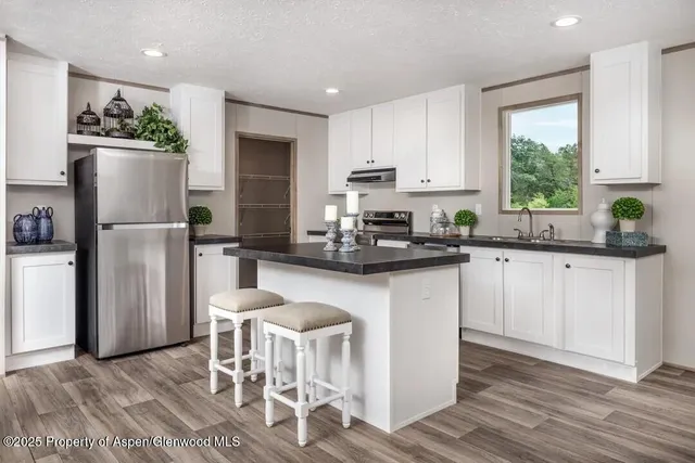a kitchen with a refrigerator a counter space dining table and chairs