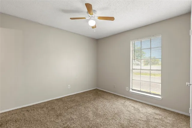 an empty room with a window and a ceiling fan