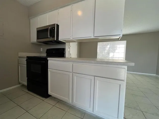 a kitchen with white cabinets and black appliances