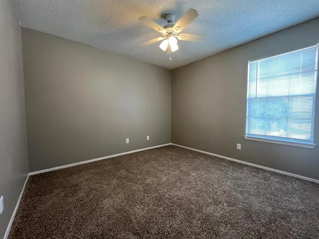 an empty room with a chandelier fan and windows