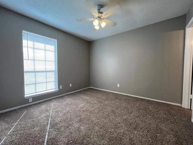 an empty room with a window and a ceiling fan