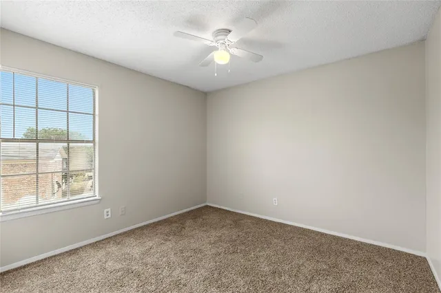 an empty room with a window and a ceiling fan