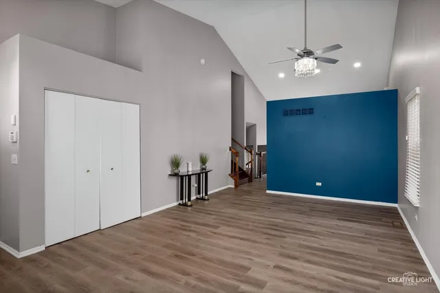 a view of an empty room with wooden floor and chandelier