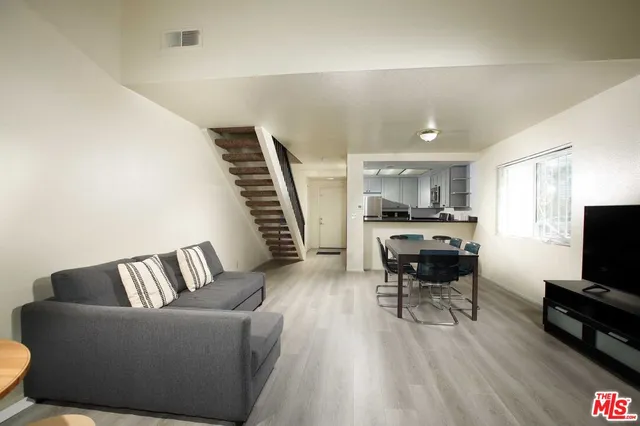 a living room with furniture and a flat screen tv with kitchen view