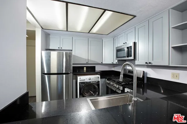 a kitchen with a refrigerator a microwave a sink and cabinets