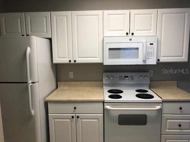 957 Salt Pond Place, Unit 101 Altamonte Springs, FL 32714 - Photo 7 of 20 a kitchen with refrigerator a stove a microwave and cabinets