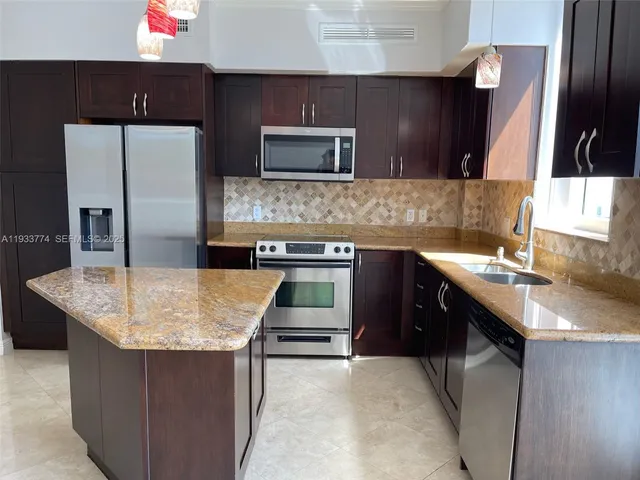a kitchen with stainless steel appliances granite countertop a sink stove and refrigerator