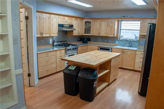 a kitchen with stainless steel appliances granite countertop a stove a sink and a refrigerator