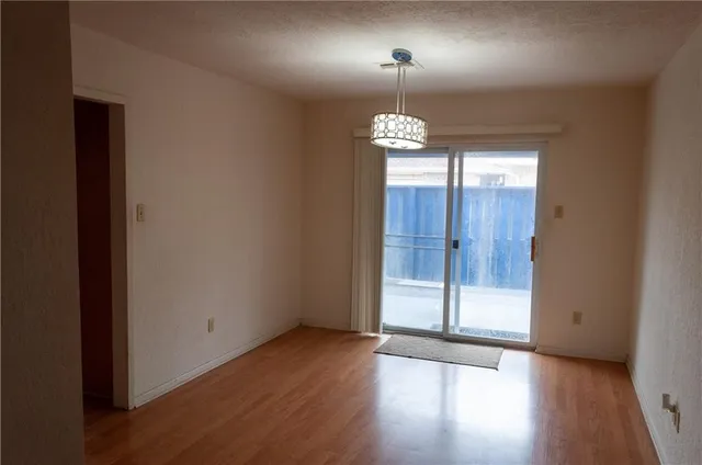 an empty room with wooden floor chandelier and windows