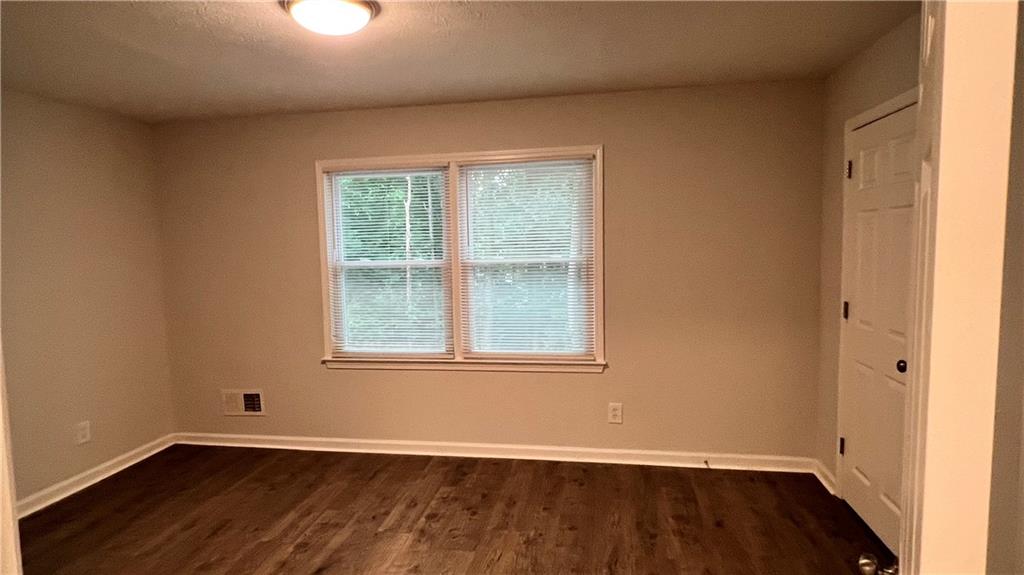 4007 Burns Road Northwest Lilburn, GA 30047 - Photo 19 of 20 an empty room with wooden floor and windows