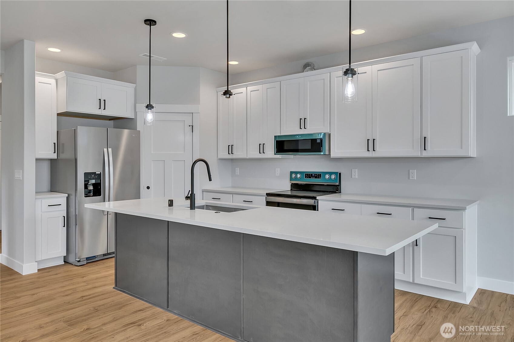 608 B Deeded Street Orting, WA 98360 - Photo 8 of 26 a kitchen with stainless steel appliances a sink a refrigerator a center island a stove and white cabinets