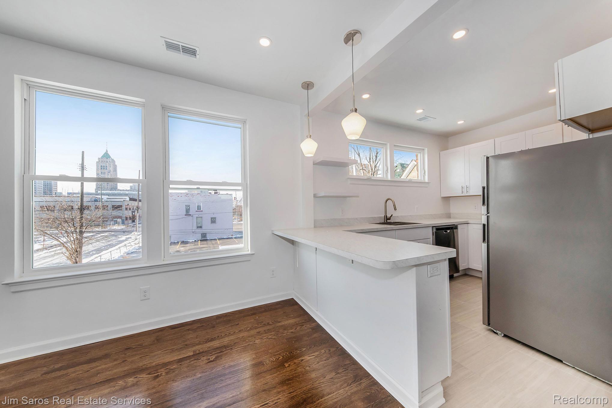 249 Custer Street Detroit, MI 48202 - Photo 7 of 22 Open-concept kitchen with white cabinetry, stainless steel appliances, and a breakfast bar with pendant lighting