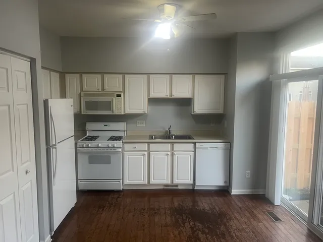 a kitchen with stainless steel appliances a refrigerator a stove a sink and white cabinets with wooden floor