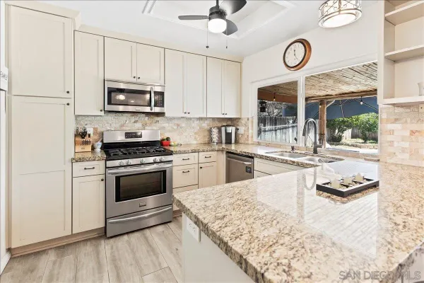 a kitchen with stainless steel appliances granite countertop a stove a sink and a microwave