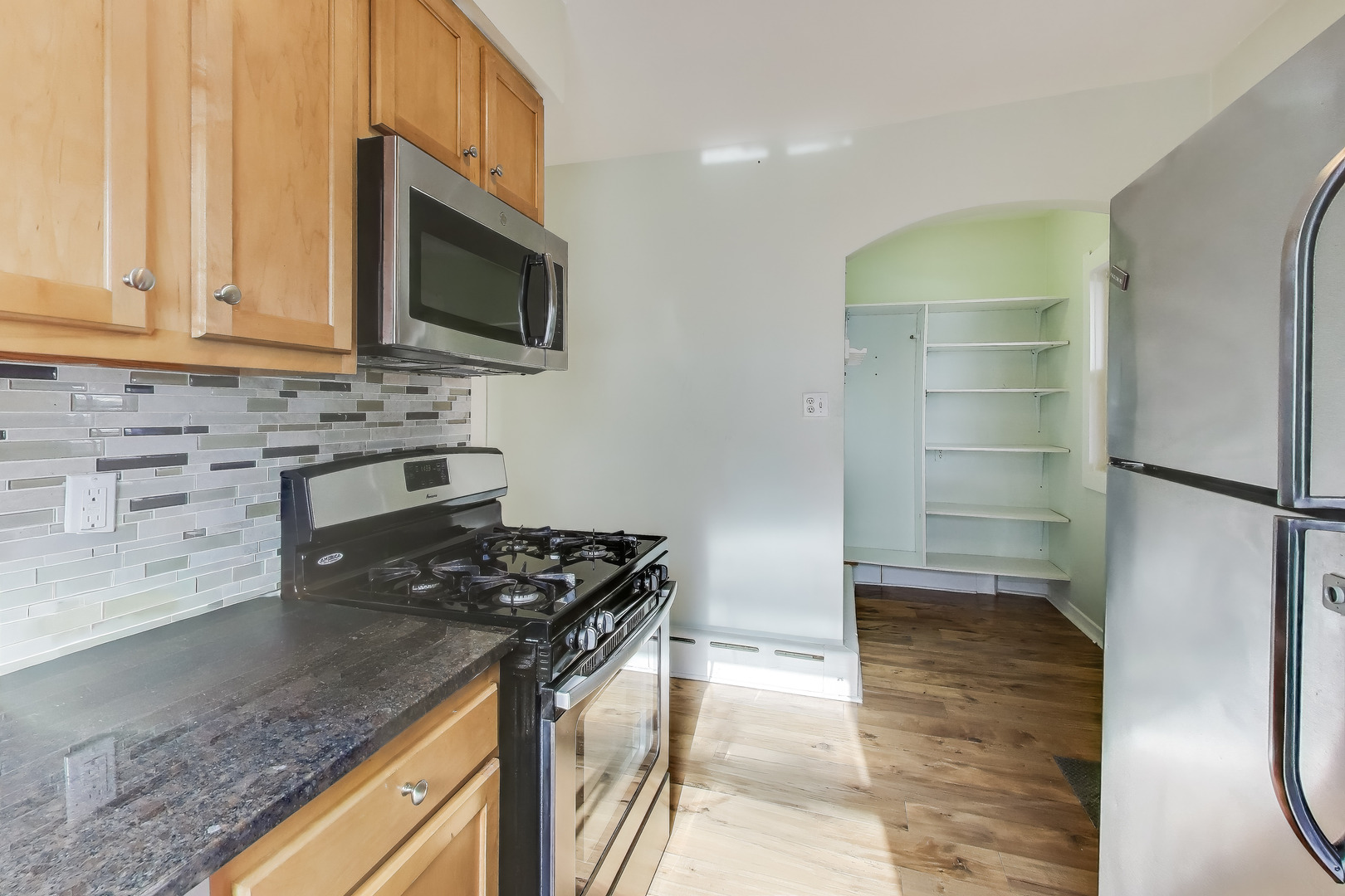 620 Elgin Avenue, Unit 2 Forest Park, IL 60130 - Photo 4 of 25 a kitchen with stainless steel appliances granite countertop a stove a sink and a microwave