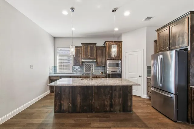 a kitchen with kitchen island a counter top space stainless steel appliances and cabinets