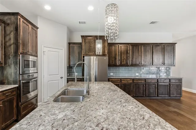 a kitchen with stainless steel appliances granite countertop a sink refrigerator and cabinets