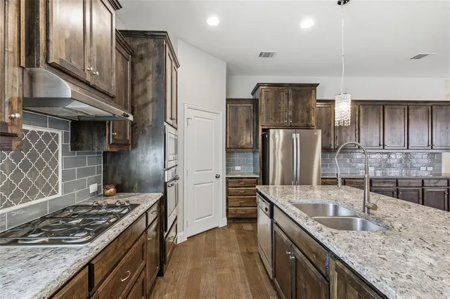 a kitchen with stainless steel appliances granite countertop a sink stove and refrigerator