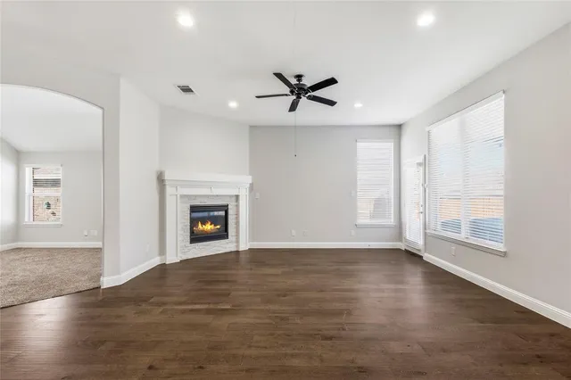 an empty room with wooden floor fireplace and windows