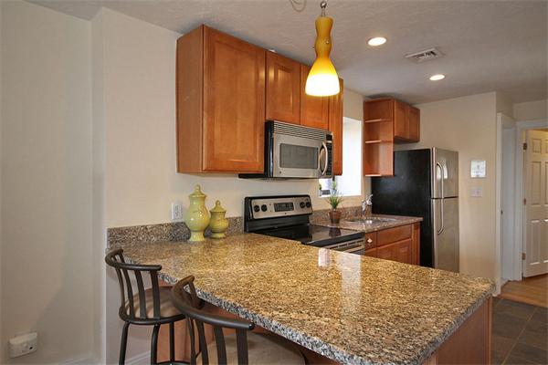 495-497 Beacon Street, Unit 10 Boston, MA 02215 - Photo 13 of 21 a kitchen with kitchen island granite countertop wooden cabinets and a refrigerator
